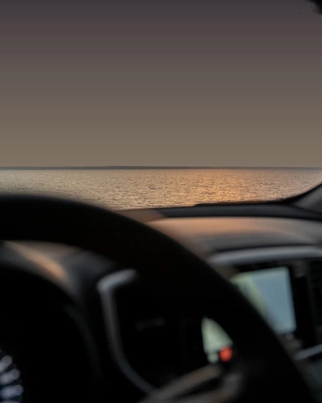 The view through a windscreen at first light, water stretching to the horizon